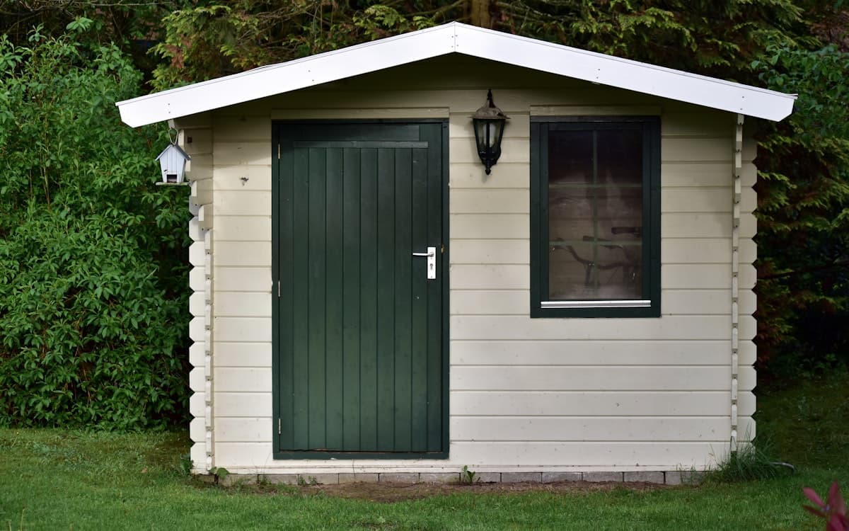 A finished garden shed with a pitched roof and painted door