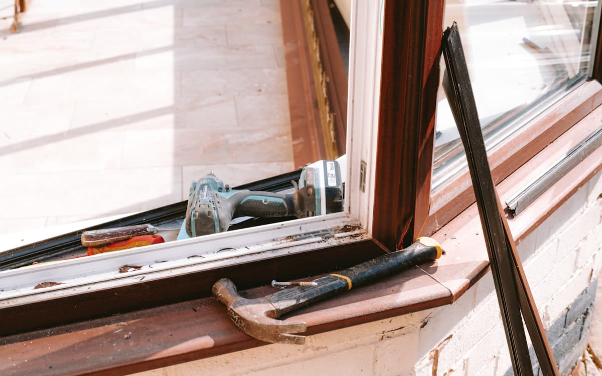 A window opening part-way through a replacement, tools on the sill